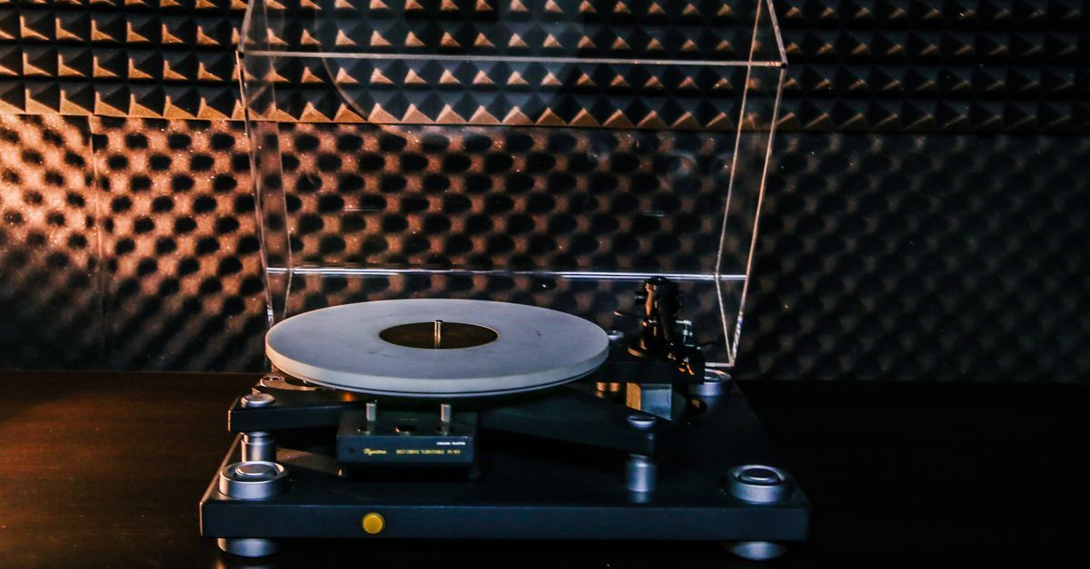 Turntable with a vinyl record on a wooden table against black acoustic foam panels