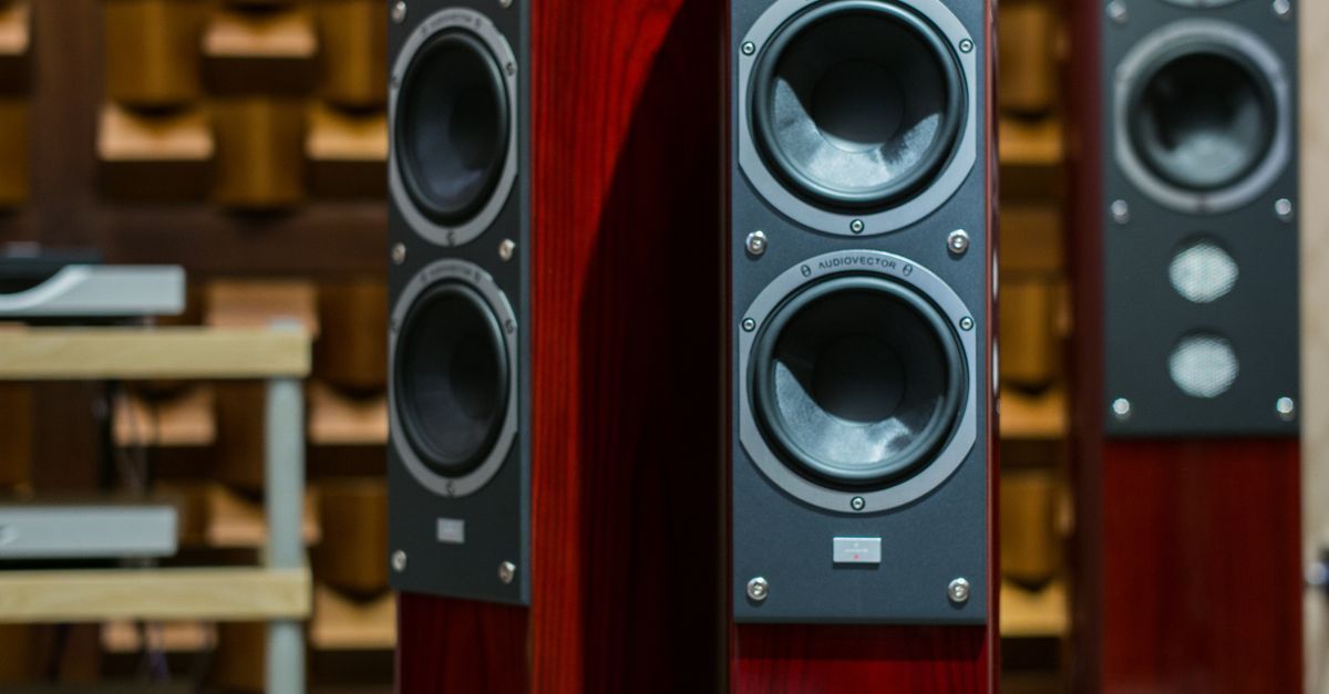 Black and wood bookshelf speakers displayed in a warm indoor showroom