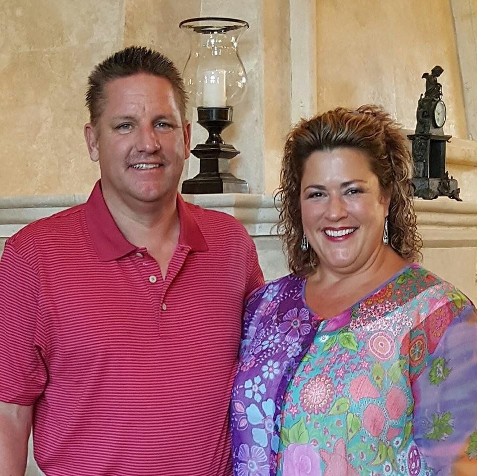 A man and a woman are posing for a picture in front of a fireplace