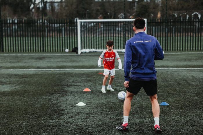 A man and a boy are playing soccer on a field.