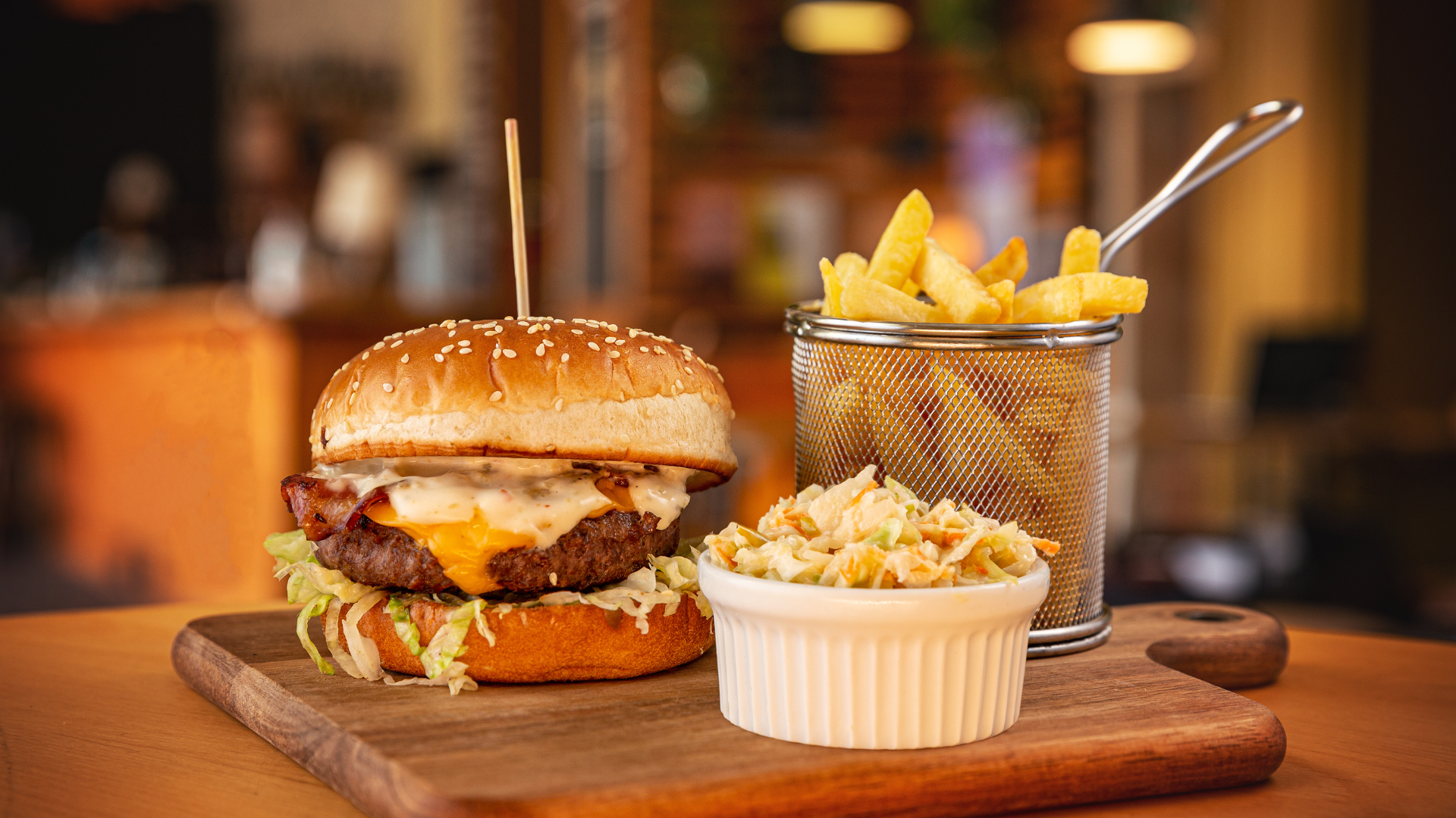 a hamburger and french fries are on a wooden cutting board