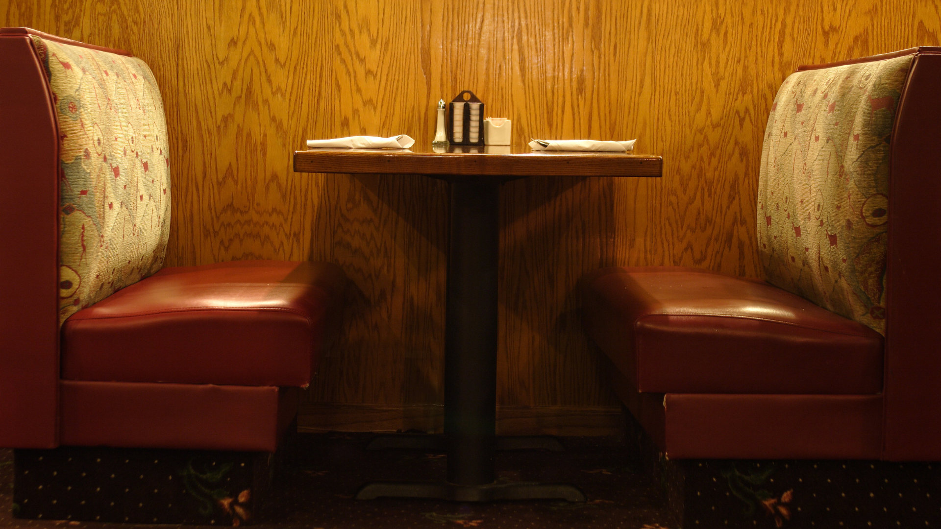 a diner booth with a table and two chairs in front of a wooden wall