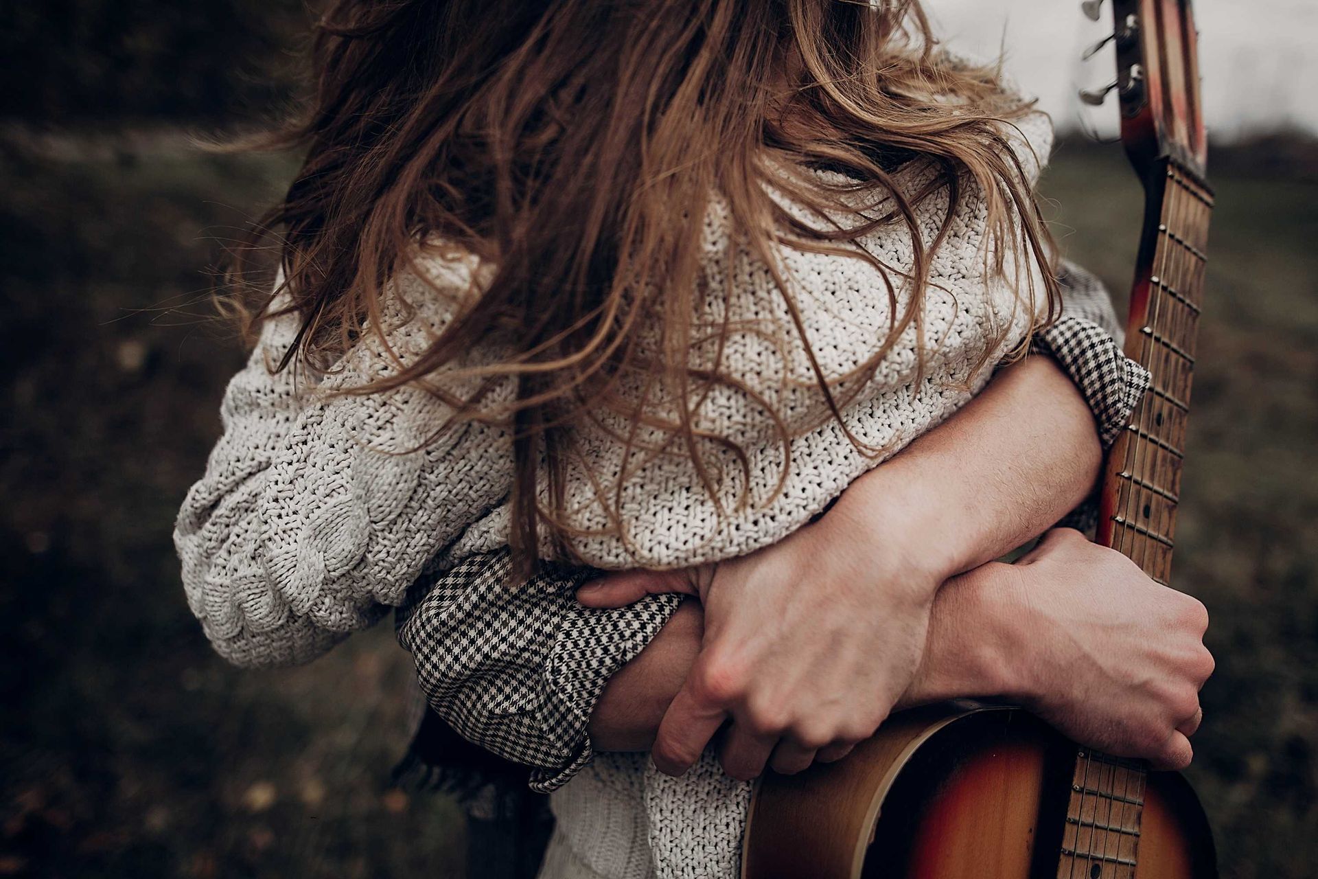 A woman (Amanda) and her new hubby hugging outside with a guitar, glad to start their new family