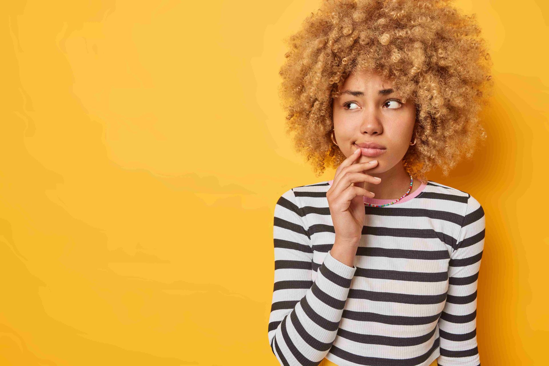 A woman with light brown hair and yellow background in photograph