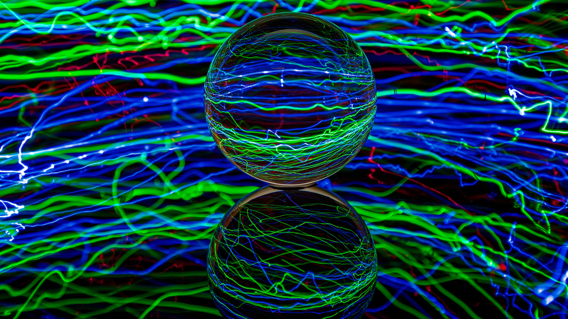 A glass ball is sitting on top of another glass ball on a colorful background.