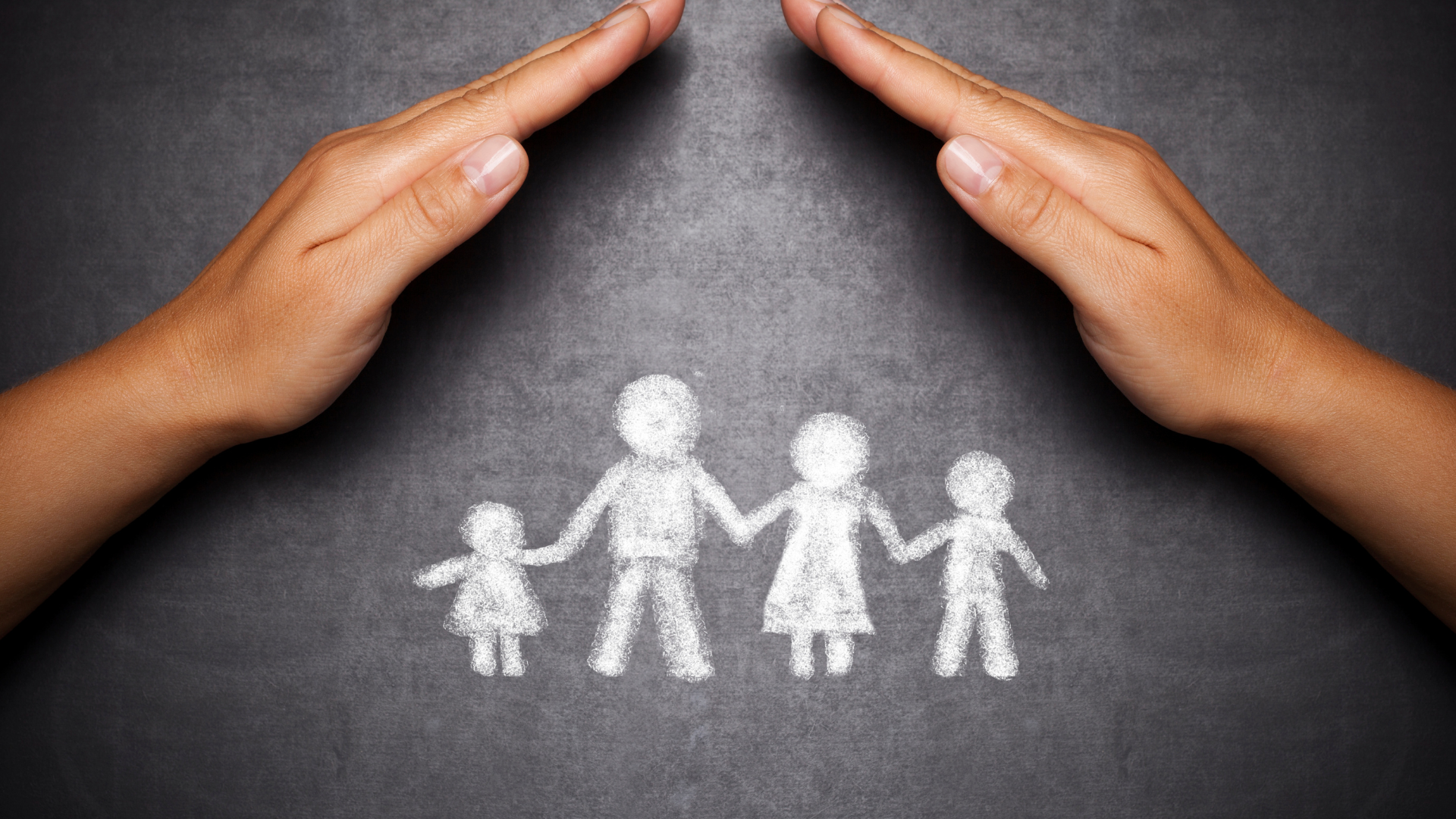 A person 's hands are covering a drawing of a family on a blackboard.