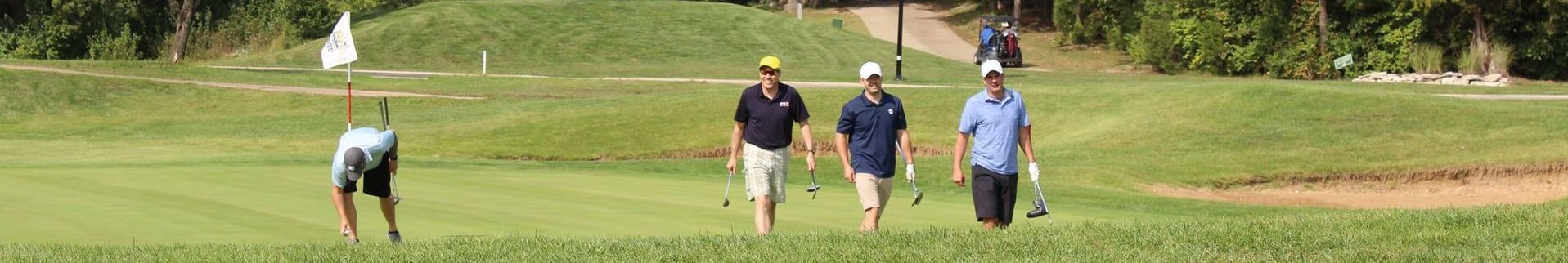 A group of people are walking on a golf course.