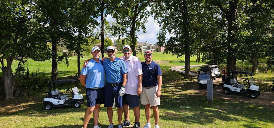 A group of men are posing for a picture on a golf course.