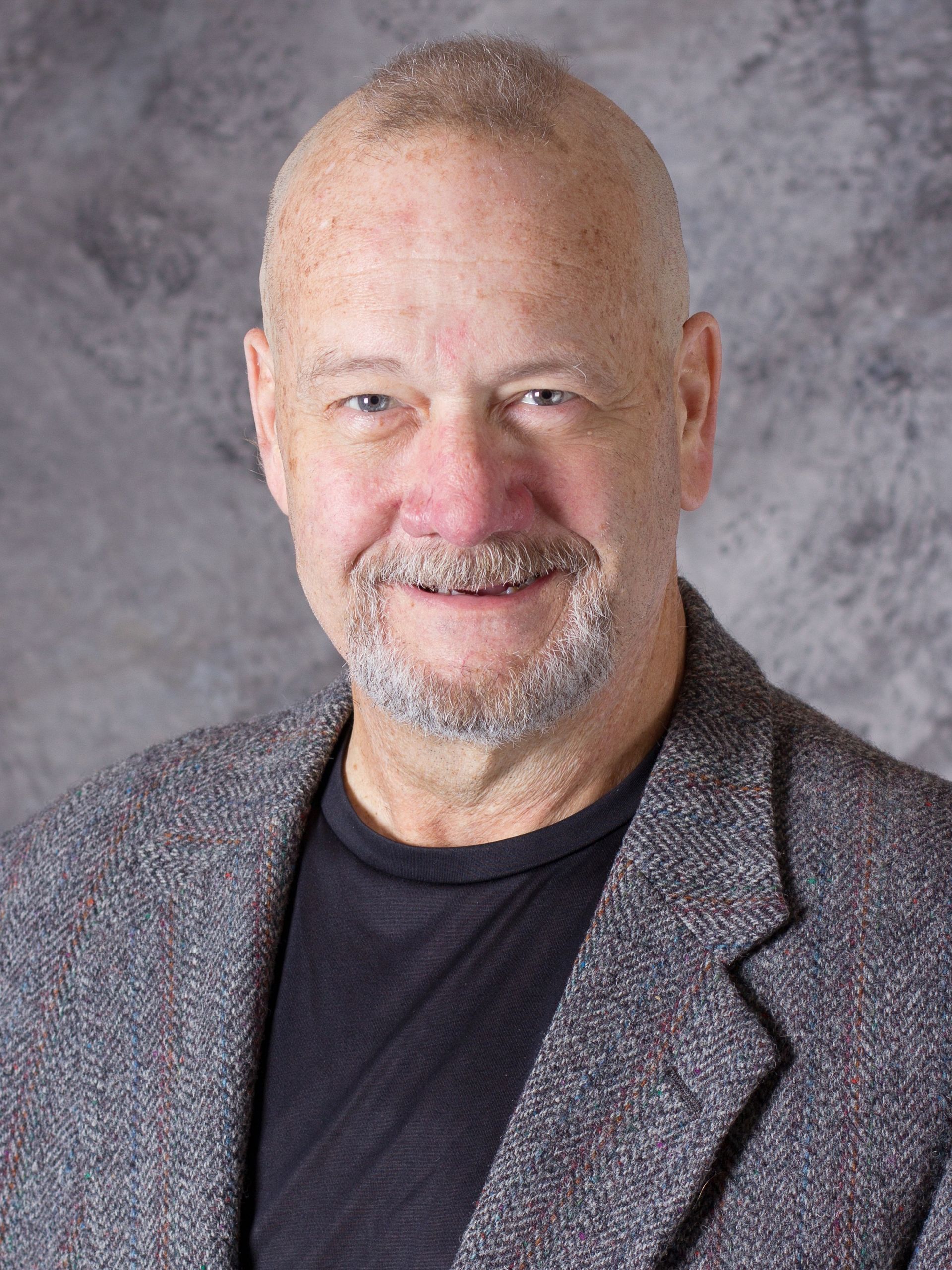A man in a suit and tie is smiling for the camera.