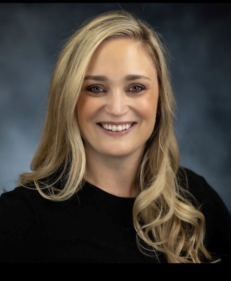The woman is wearing a black jacket and smiling for the camera.