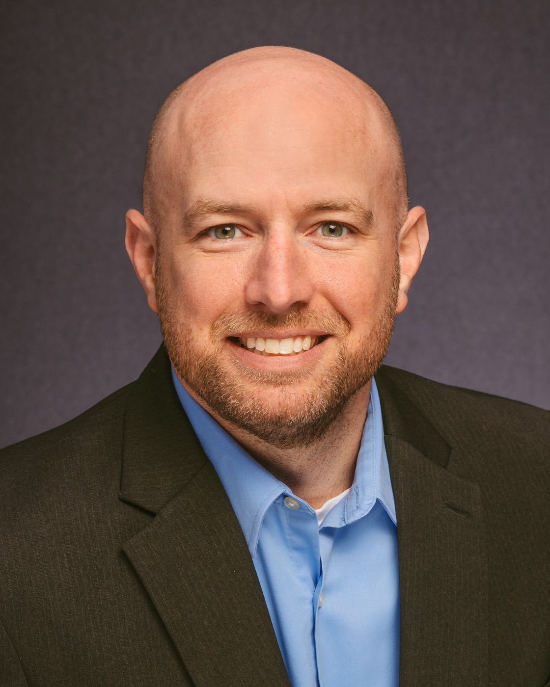 A man in a suit and tie is smiling for the camera.