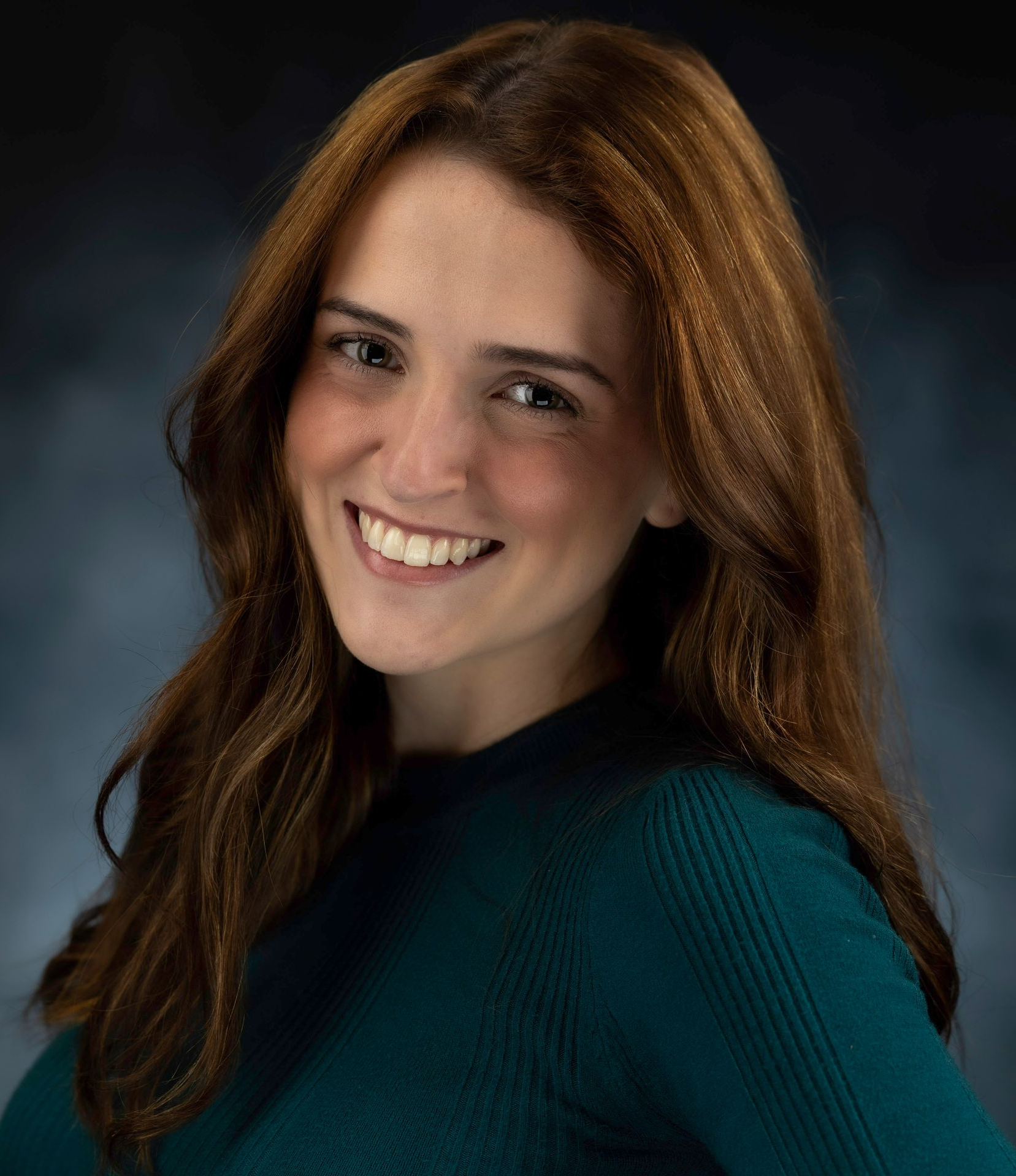 A woman in a black jacket and green shirt is smiling for the camera.