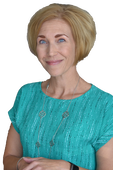 A woman in a blue shirt is smiling and looking at the camera.