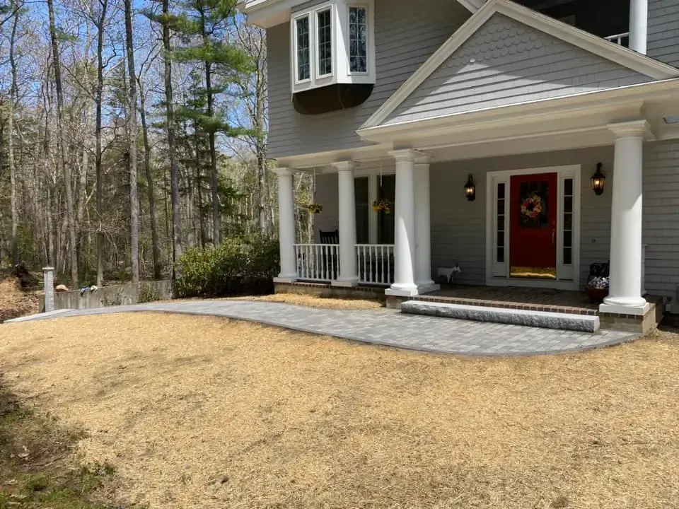A large house with a red door and a porch surrounded by trees.