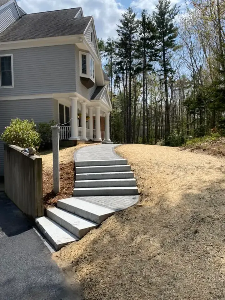 A house with stairs leading up to it and trees in the background.