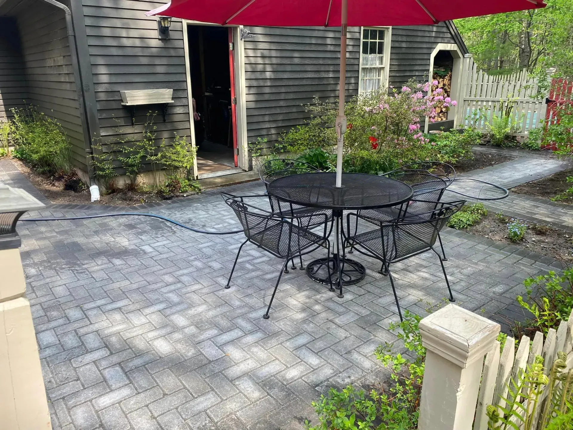 A patio with a table and chairs and an umbrella in front of a house.