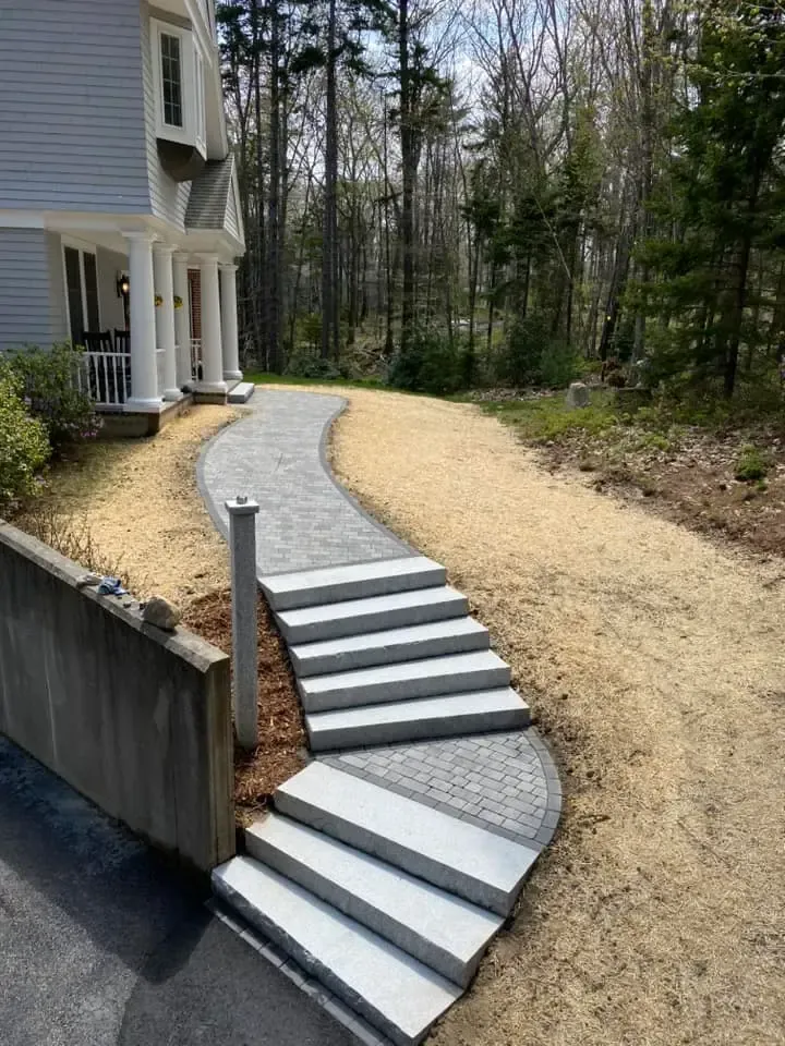 A walkway with stairs leading to a house in the woods.