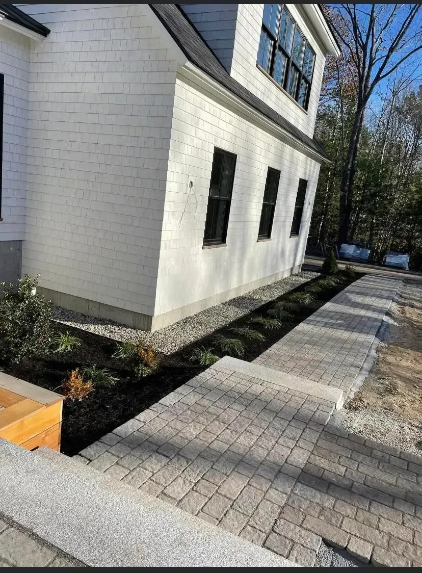 A white house with a brick walkway leading to it.