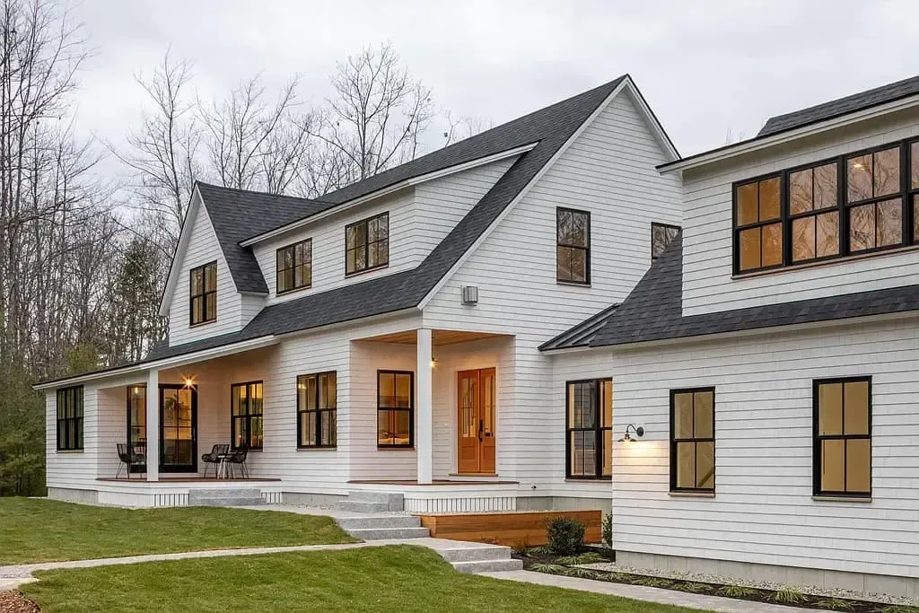 A large white house with a black roof and a large porch.