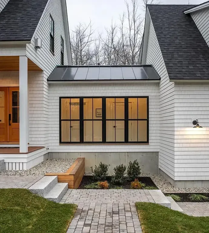 A white house with black windows and a brick walkway