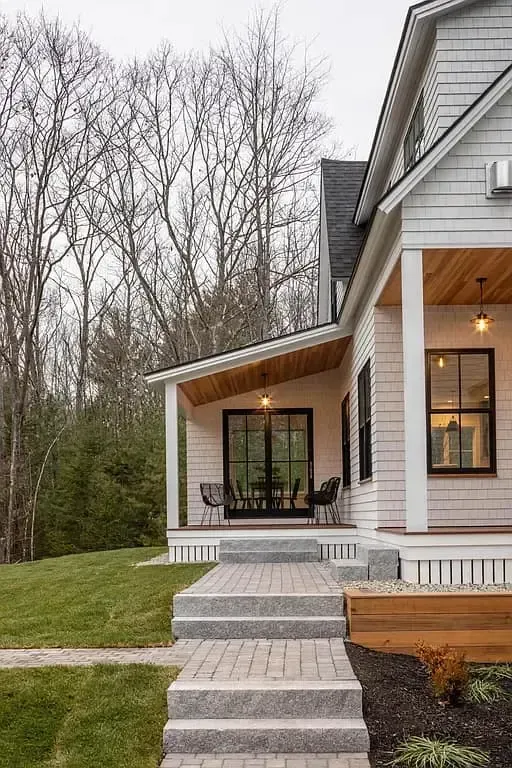 A white house with a porch and stairs leading to it.