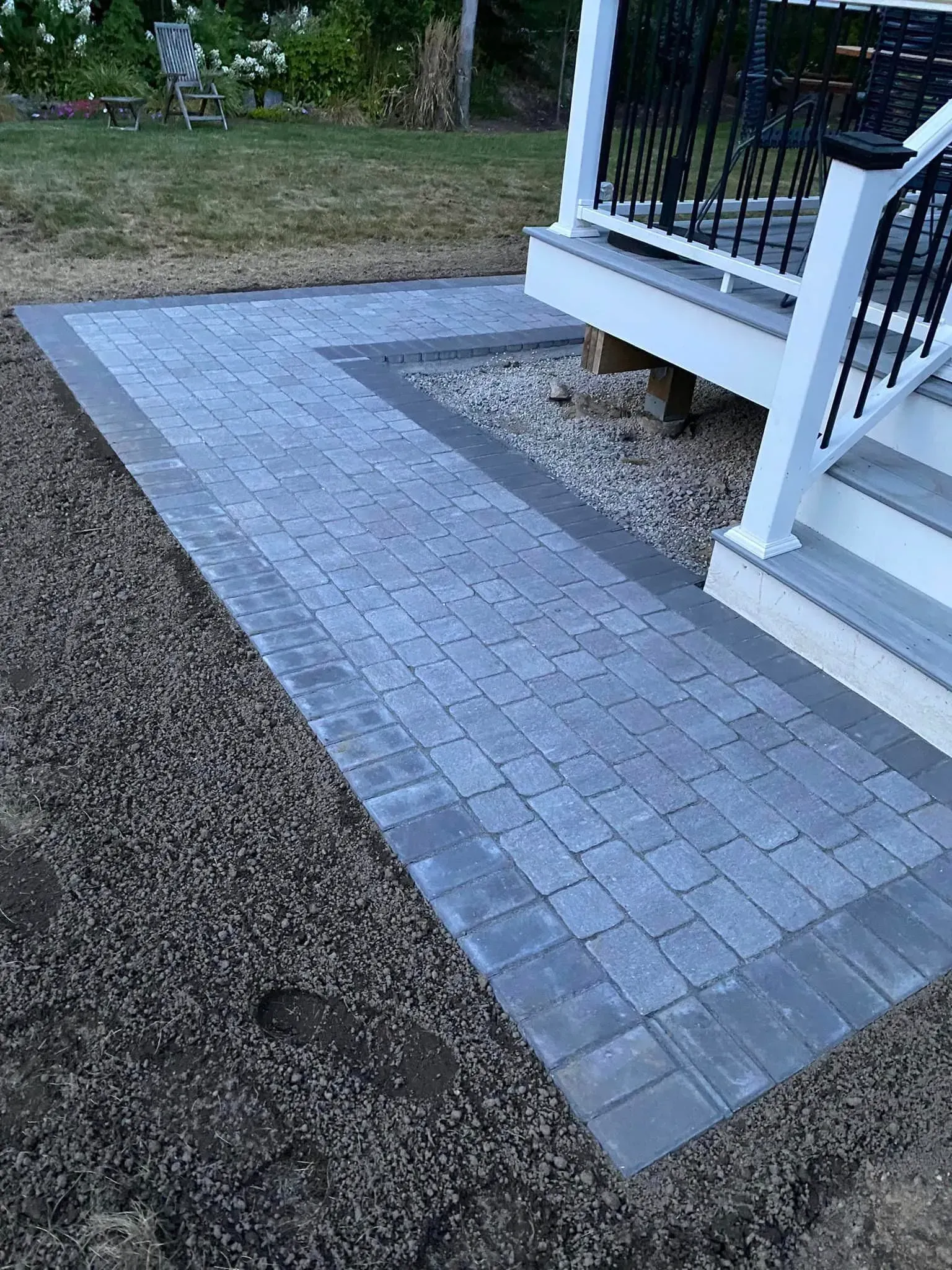 A patio with a walkway leading to a porch and stairs.