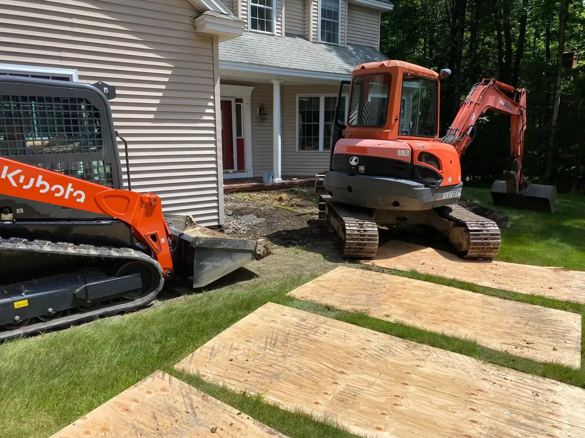 Two tractors are parked in front of a house.
