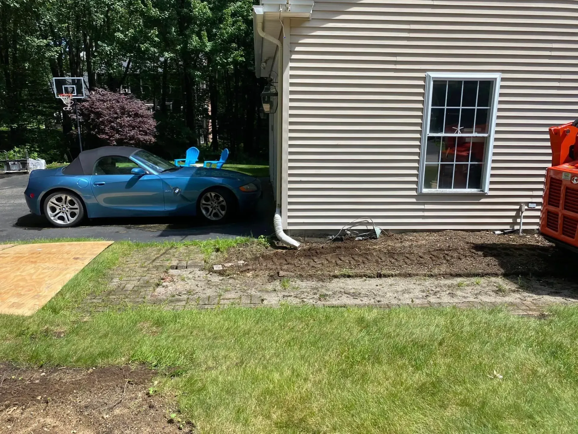 A blue car is parked in front of a house.