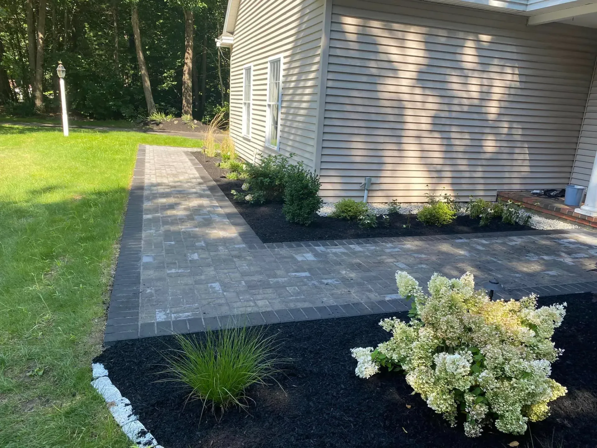 A house with a walkway leading to it and a garden in front of it.