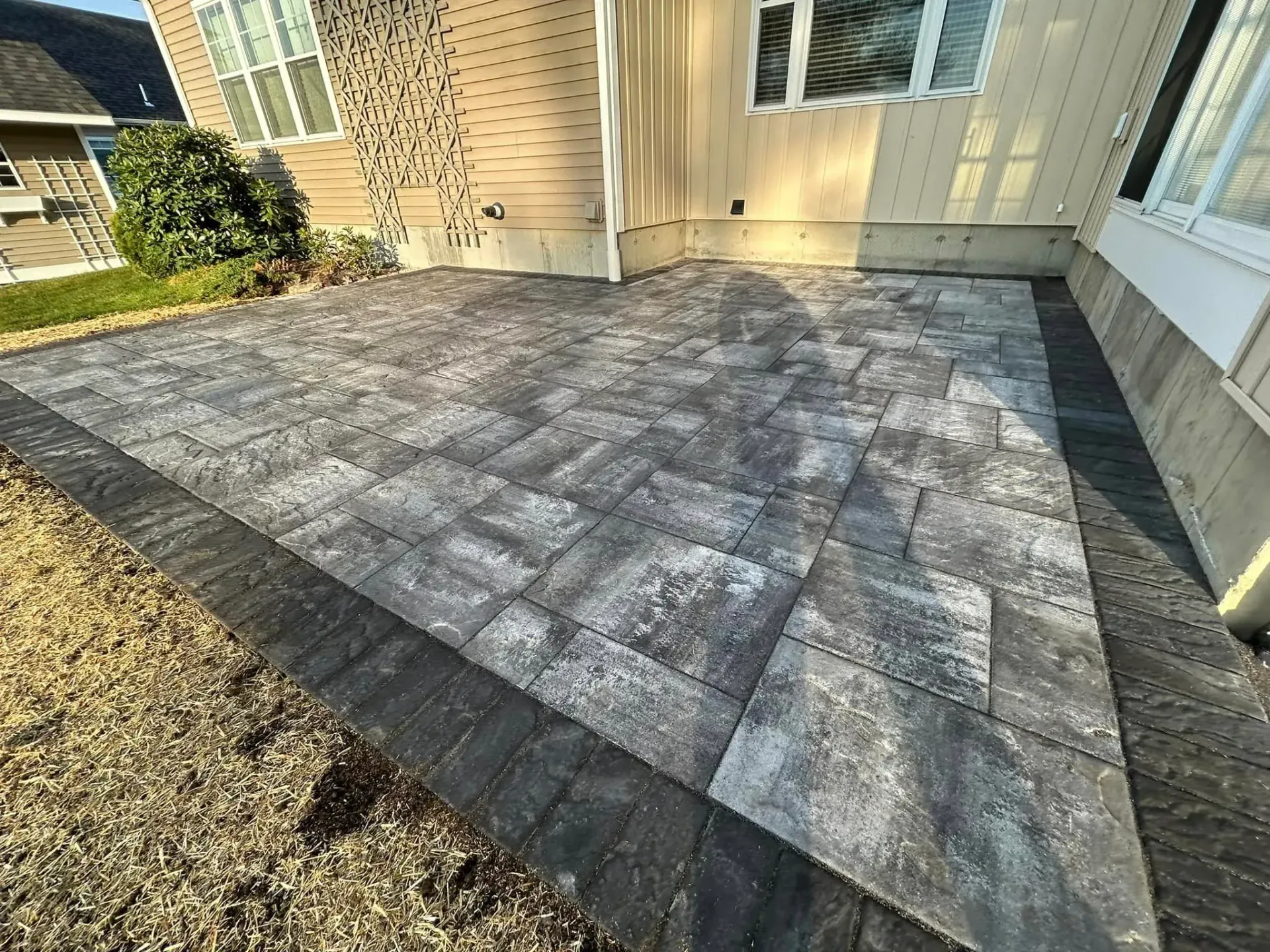 A patio with bricks and gravel in front of a house.