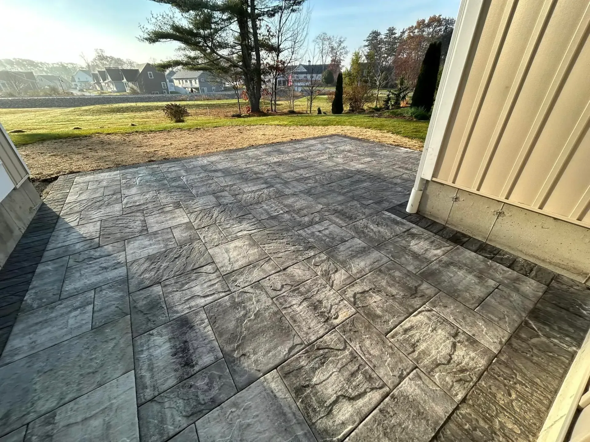 A concrete patio in front of a house with trees in the background.