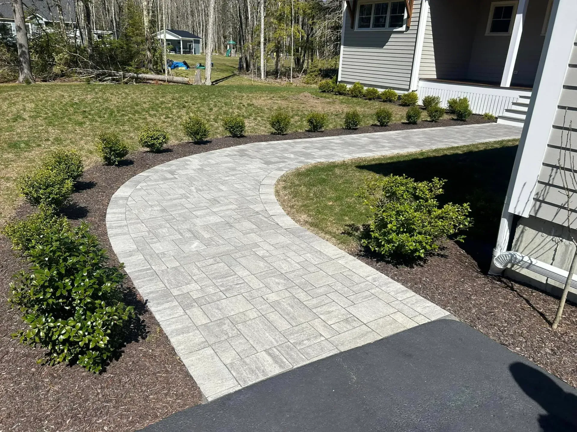 A brick walkway leading to a house in a yard.