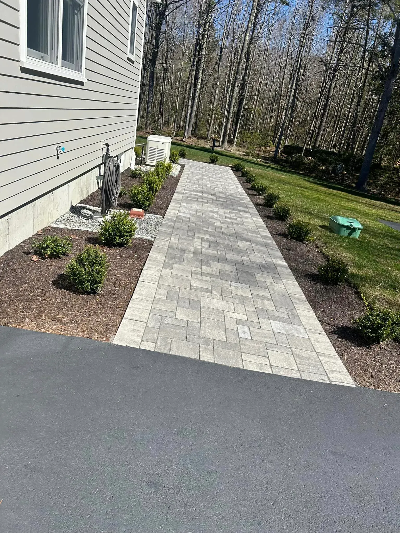 A brick walkway leading to a house next to a driveway.