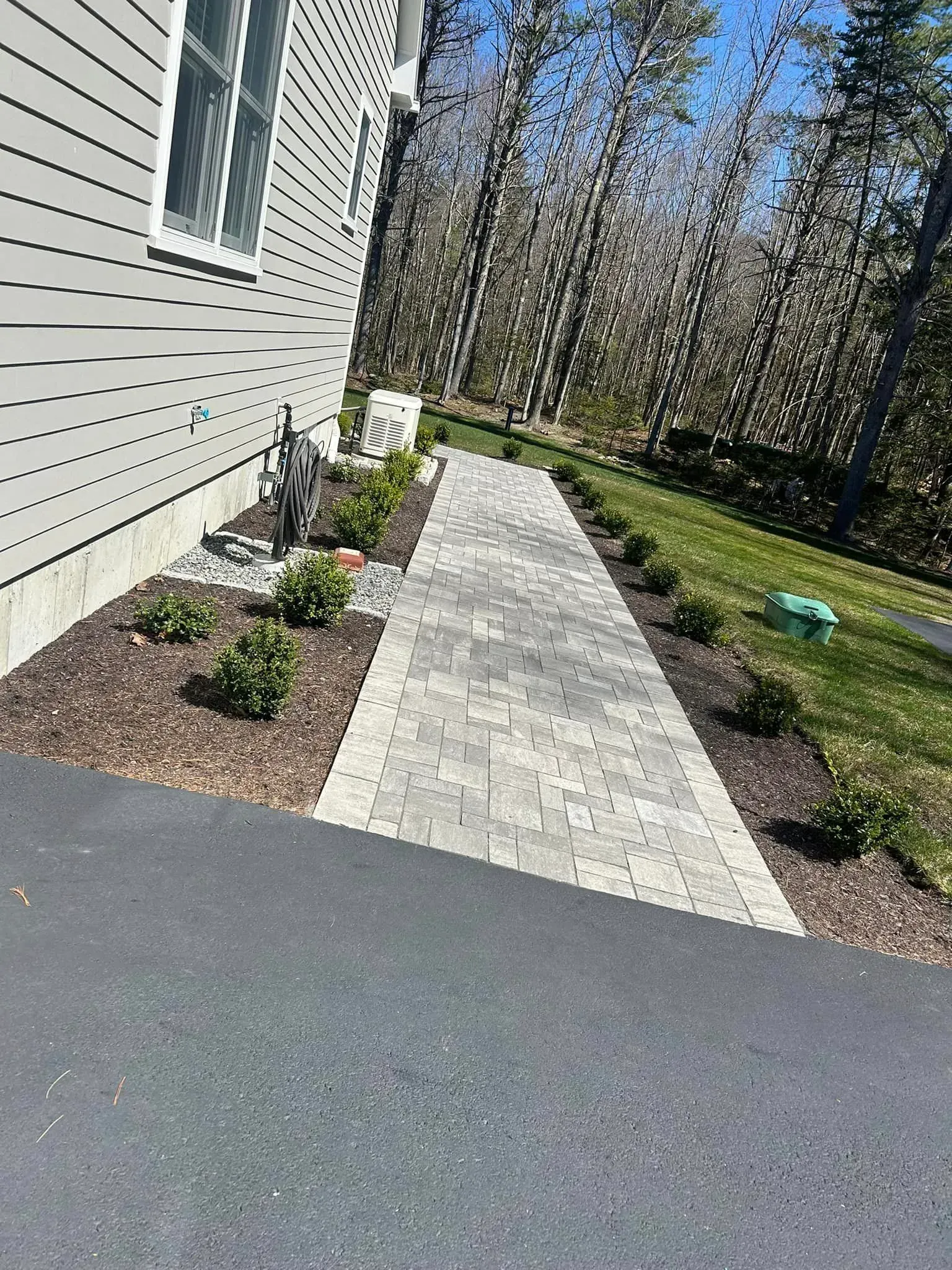 A sidewalk leading to a house with trees in the background.
