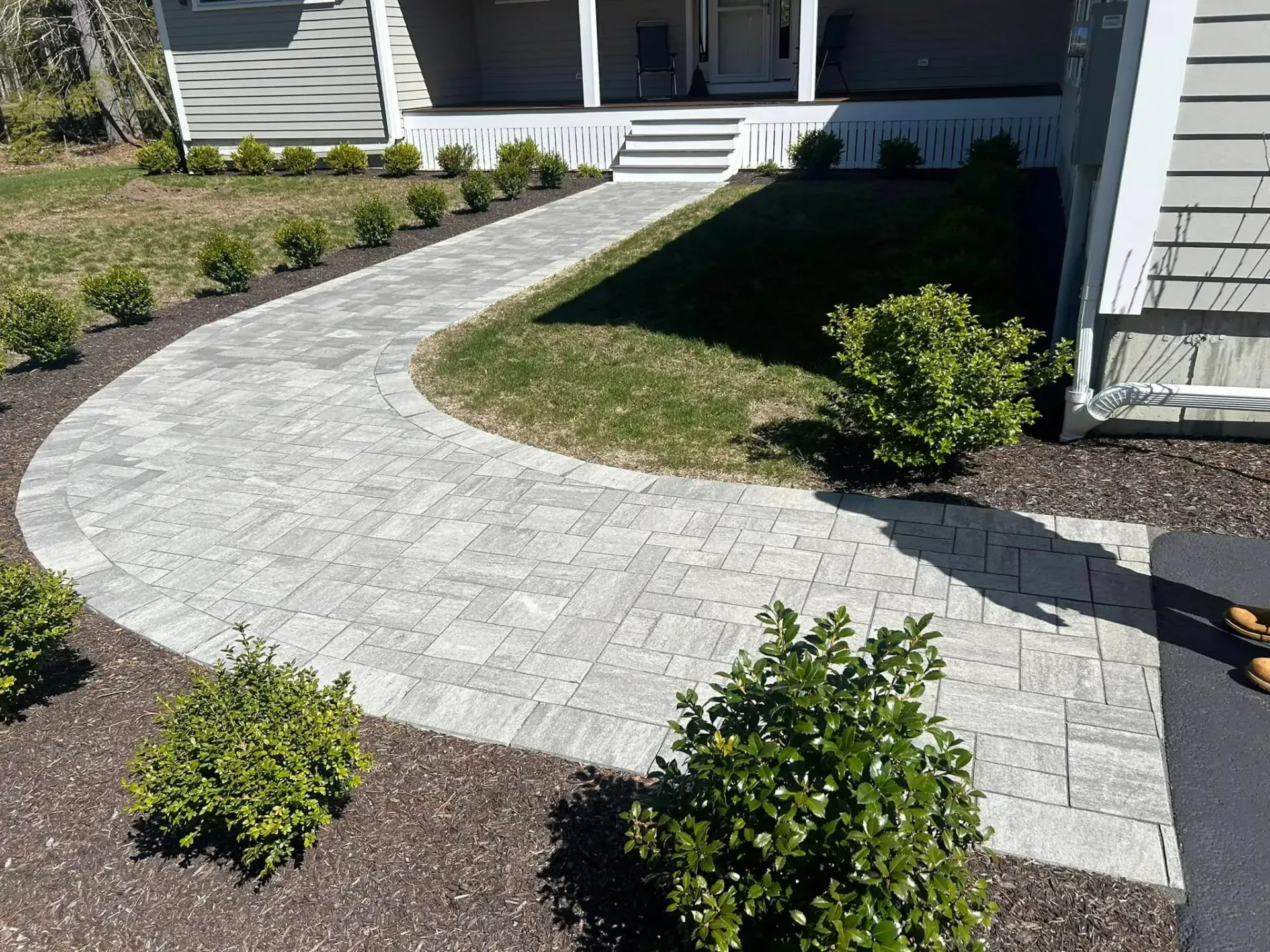A brick walkway leading to the front of a house.