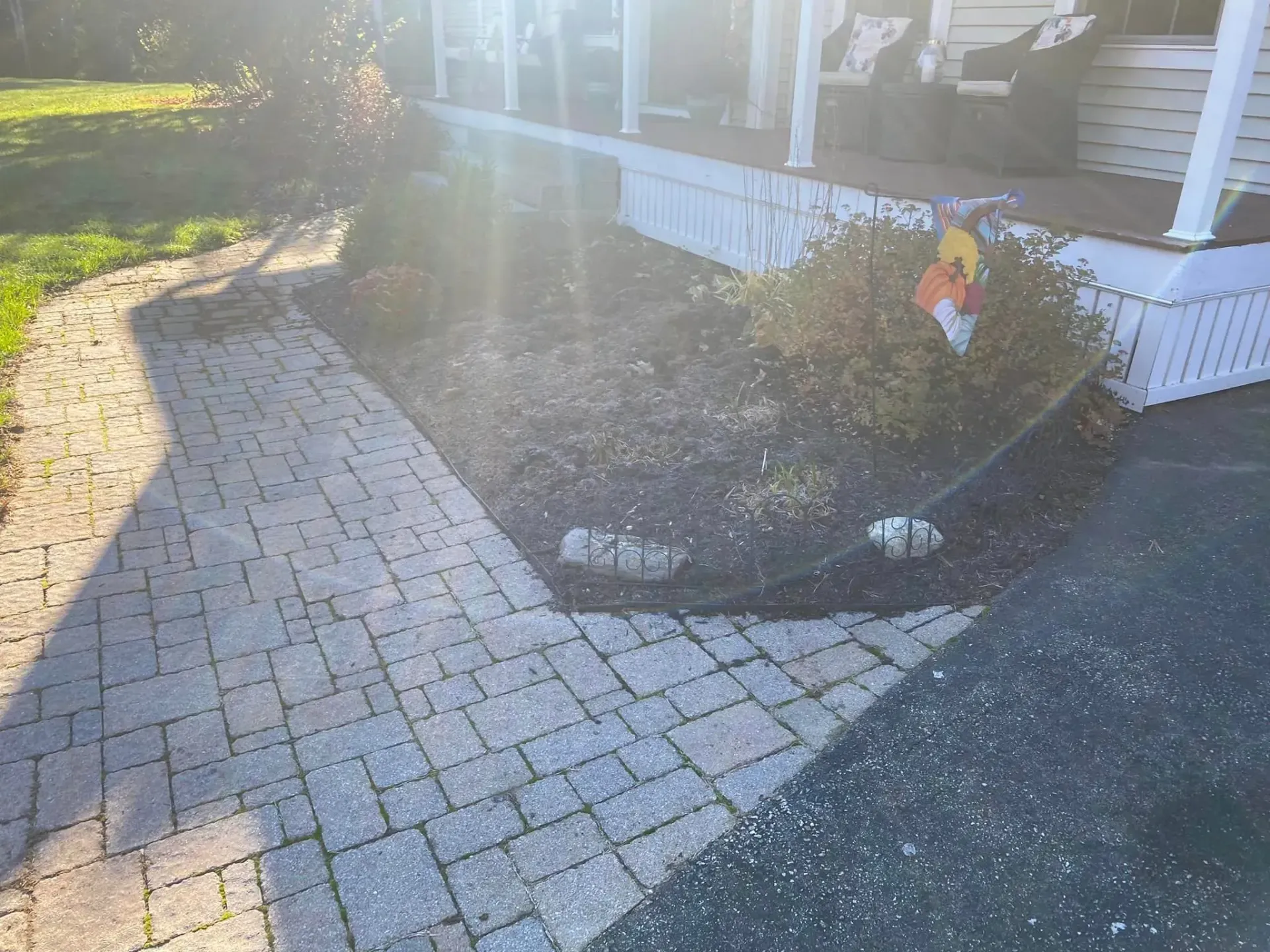 A brick walkway leading to a house with a porch.