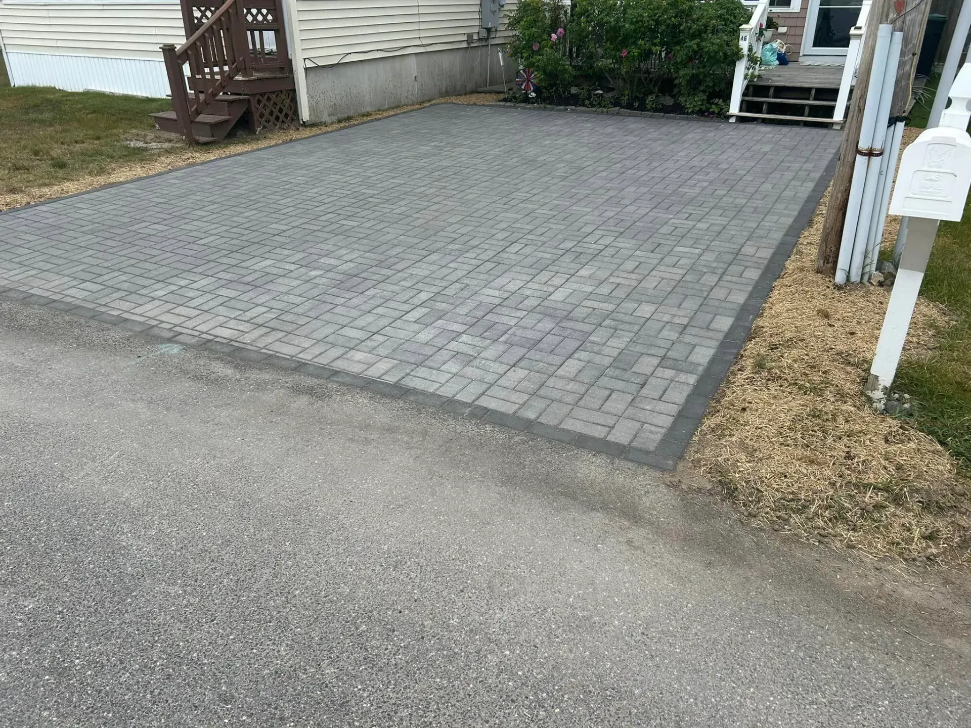 A brick driveway is being built in front of a house.