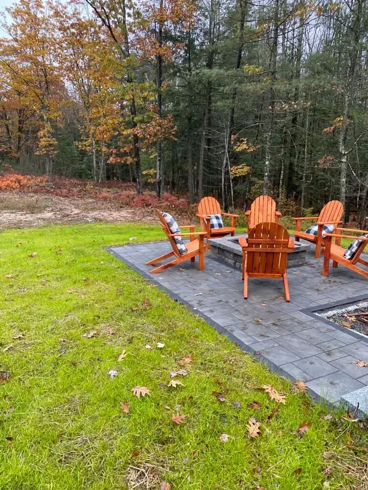 A group of wooden chairs are sitting on a patio next to a fire pit.