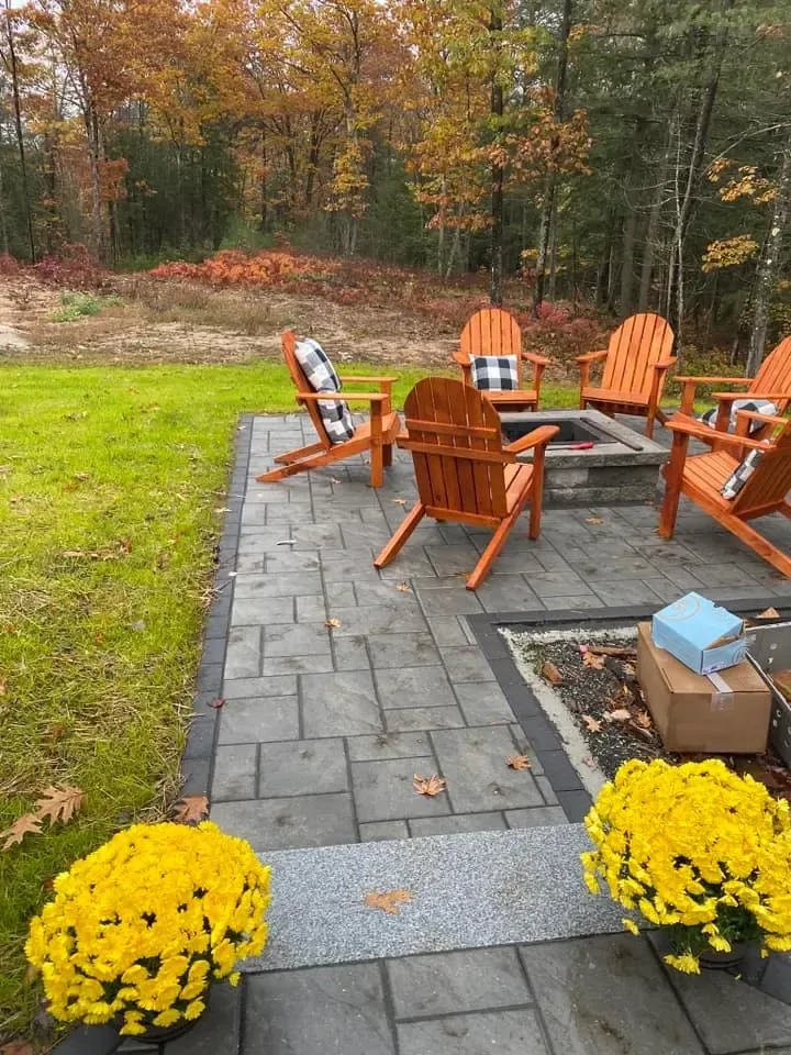 A patio with chairs and a fire pit in the middle of it.