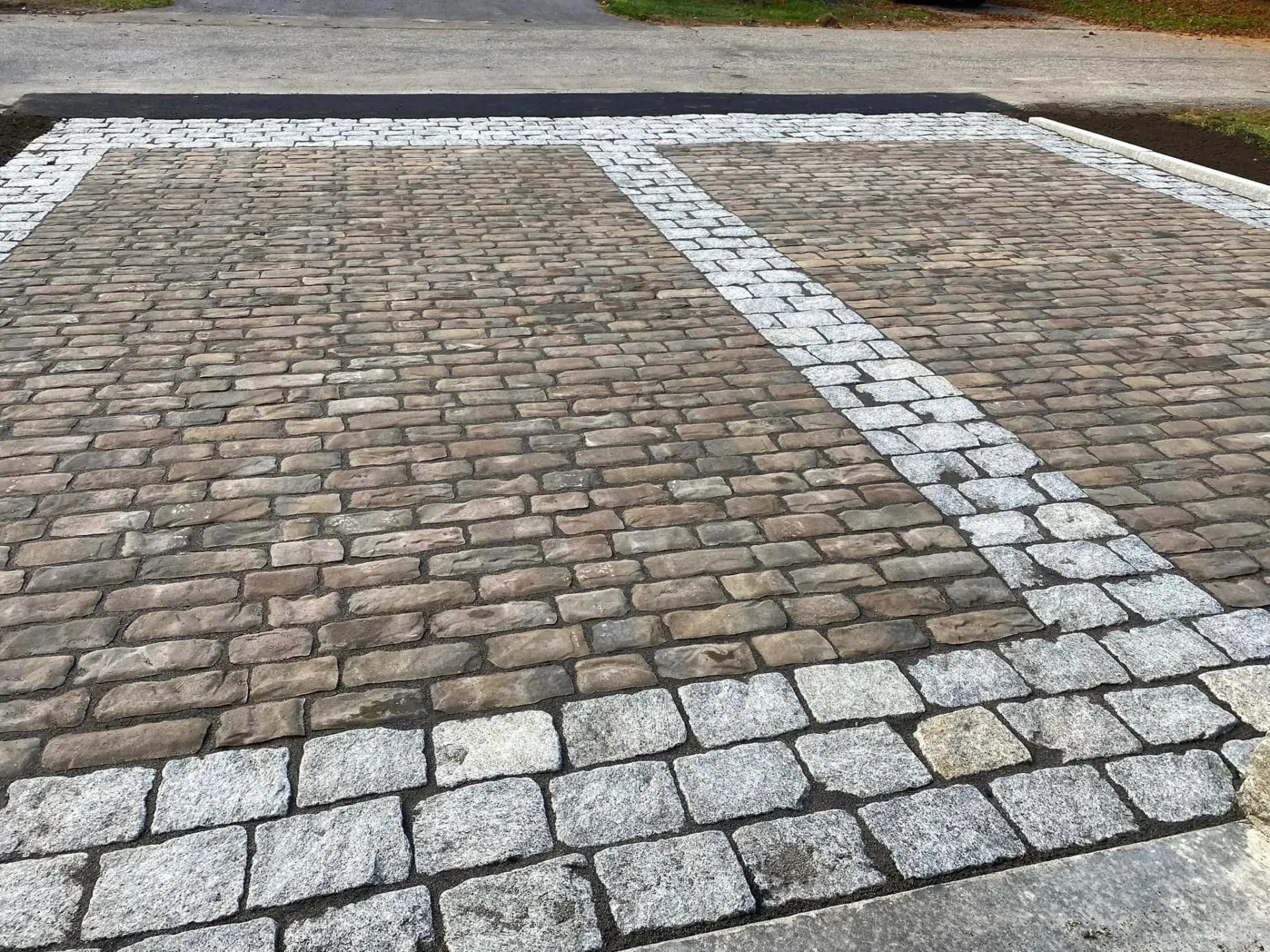 A brick driveway with a white line in the middle of it.