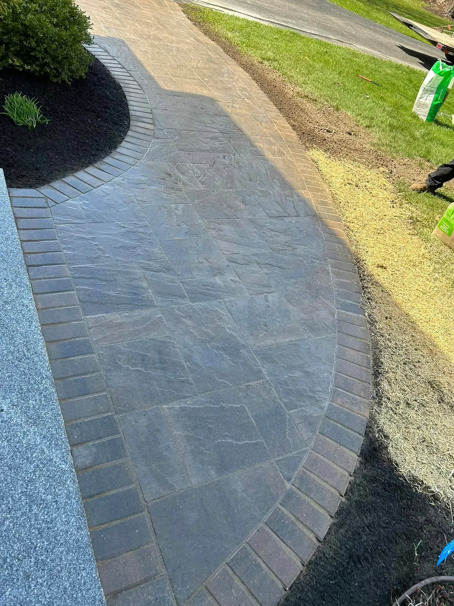 A brick walkway is being built next to a grassy area.