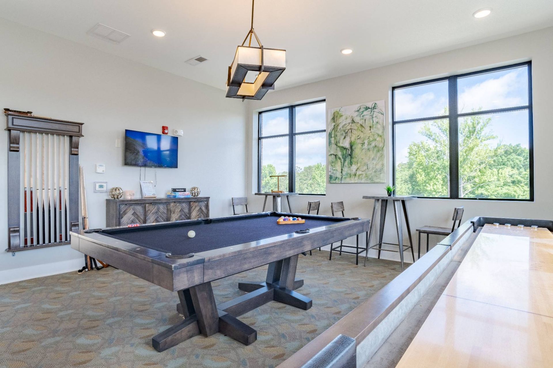 Interior community game room with a billiards table, high-top tables, and a wall TV.