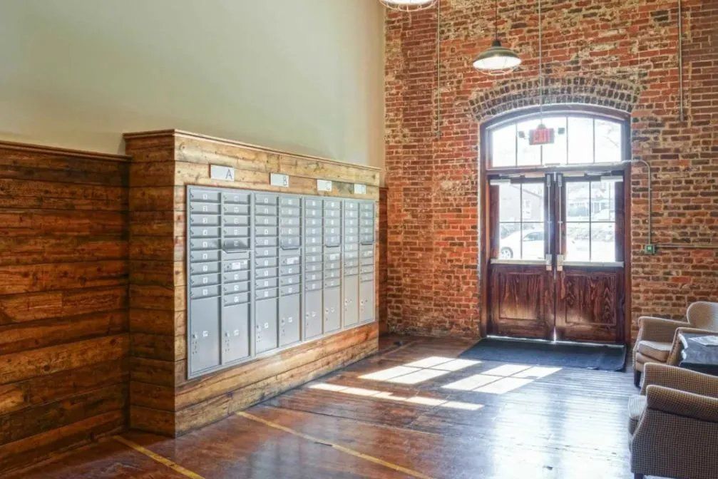 Interior view of a mailbox area in a property with a brick wall and wooden accents.
