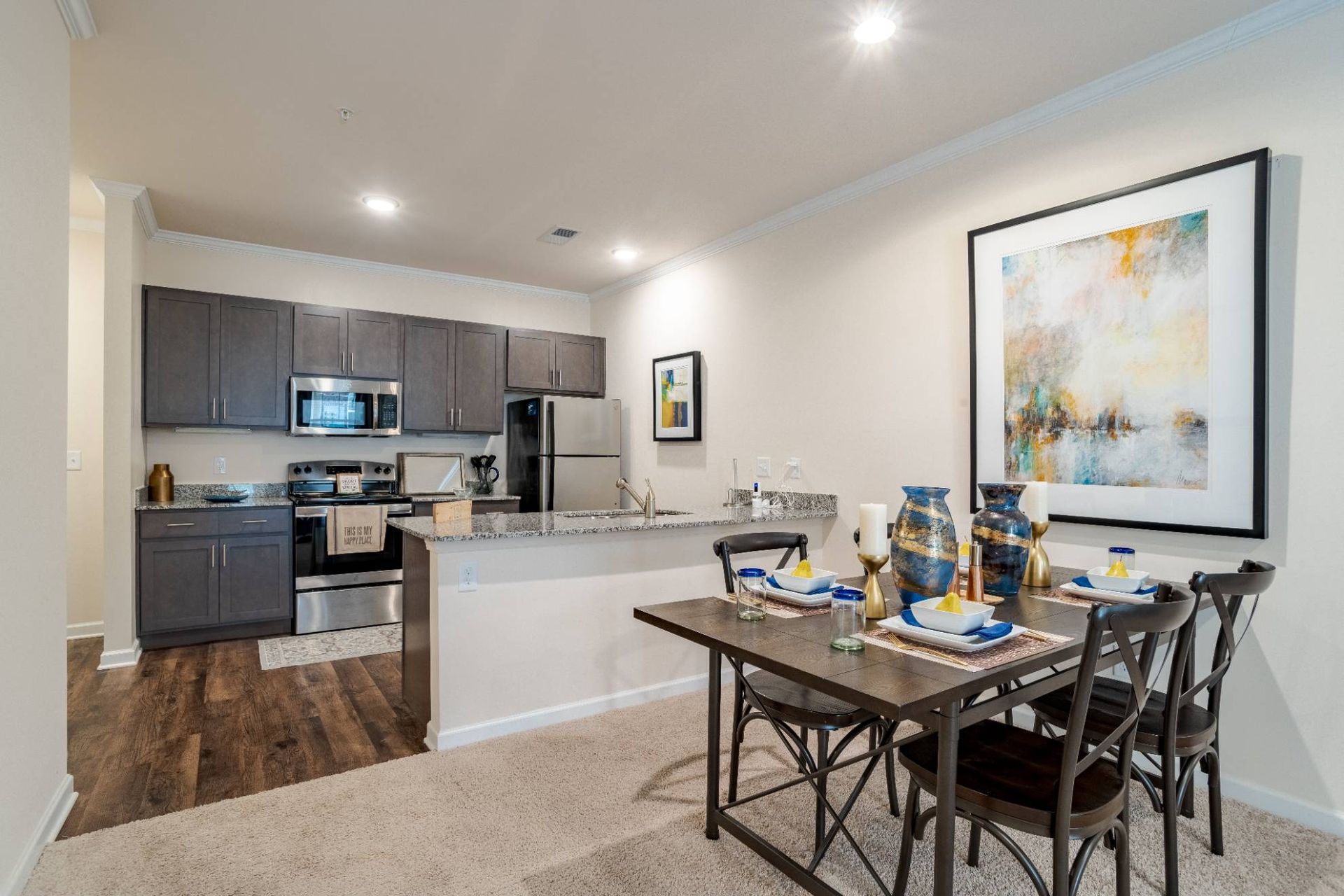 Open-concept kitchen and dining area with grey cabinets and granite countertops