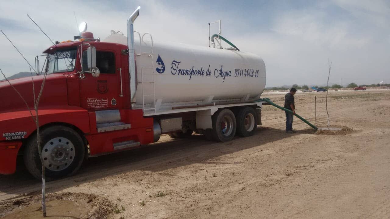 Un hombre bombea agua desde un camión cisterna en el desierto.