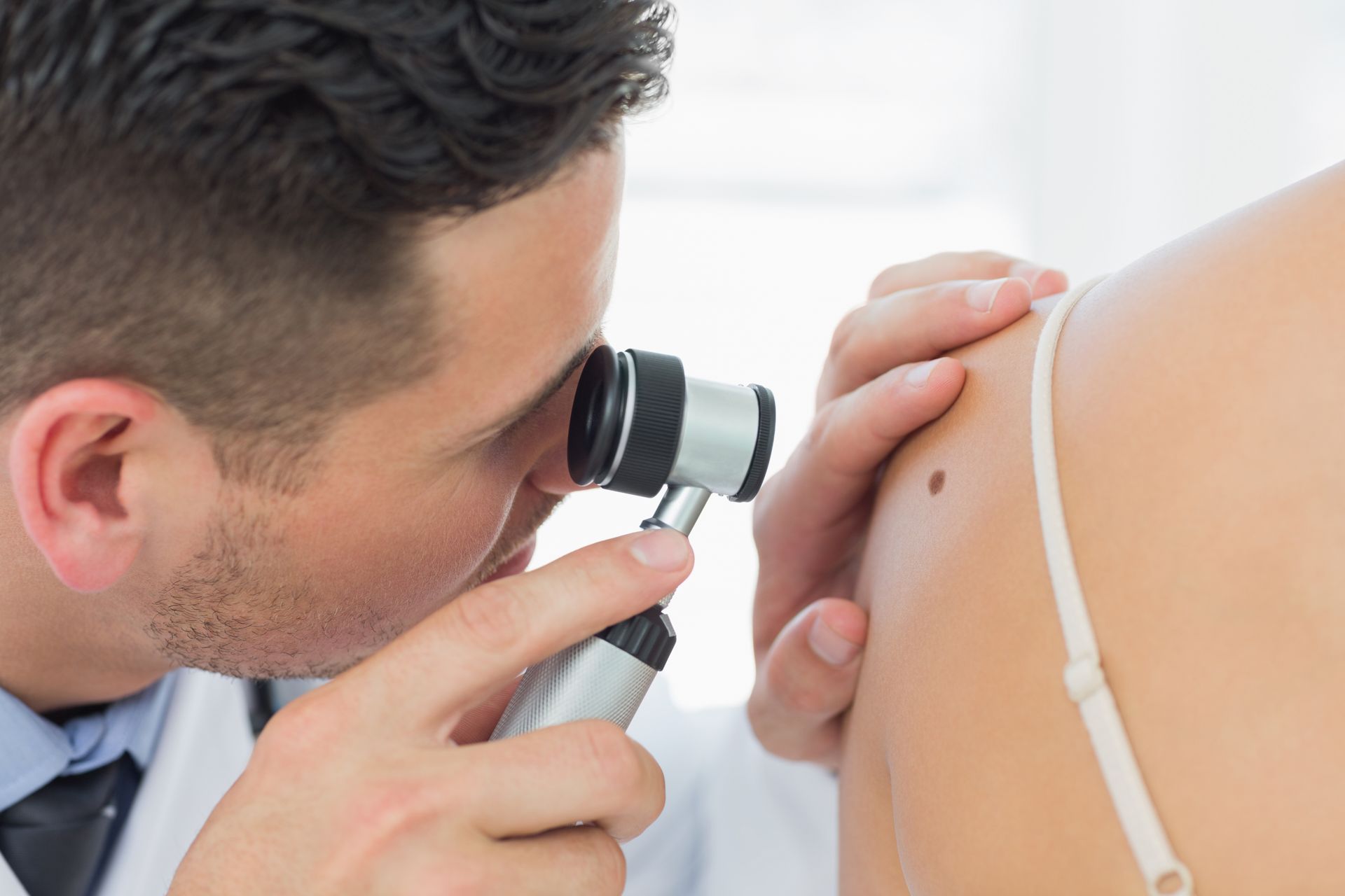 Doctor examining a patient’s shoulder with a dermatoscope