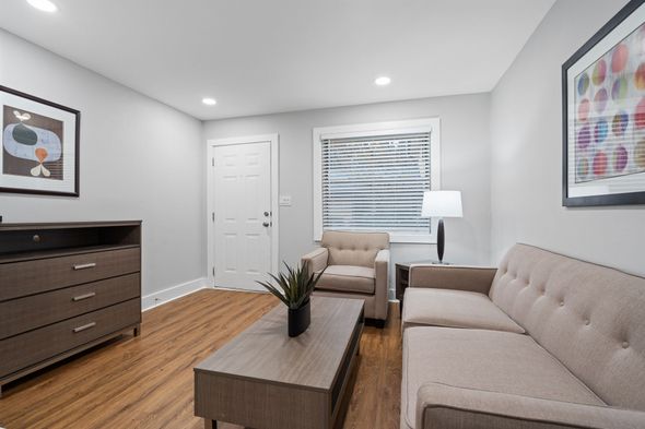 Modern living room with beige sofas, wooden coffee table, dresser, window, and floor lamp
