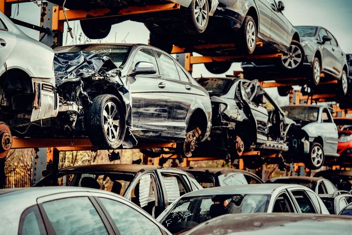 Una struttura metallica verticale a più livelli che espone numerose automobili danneggiate e recuperate in un deposito di rottami o di riciclaggio.