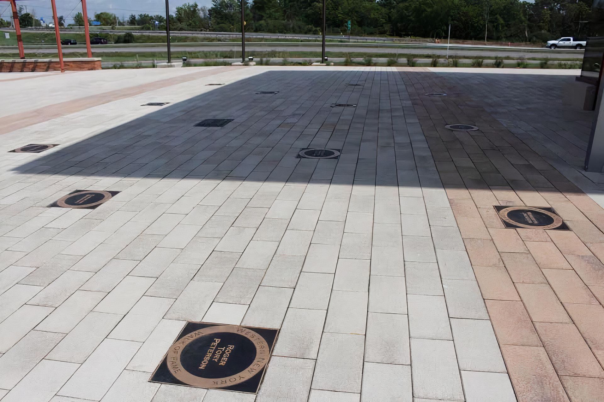 A brick walkway with a black circle with the letter m on it