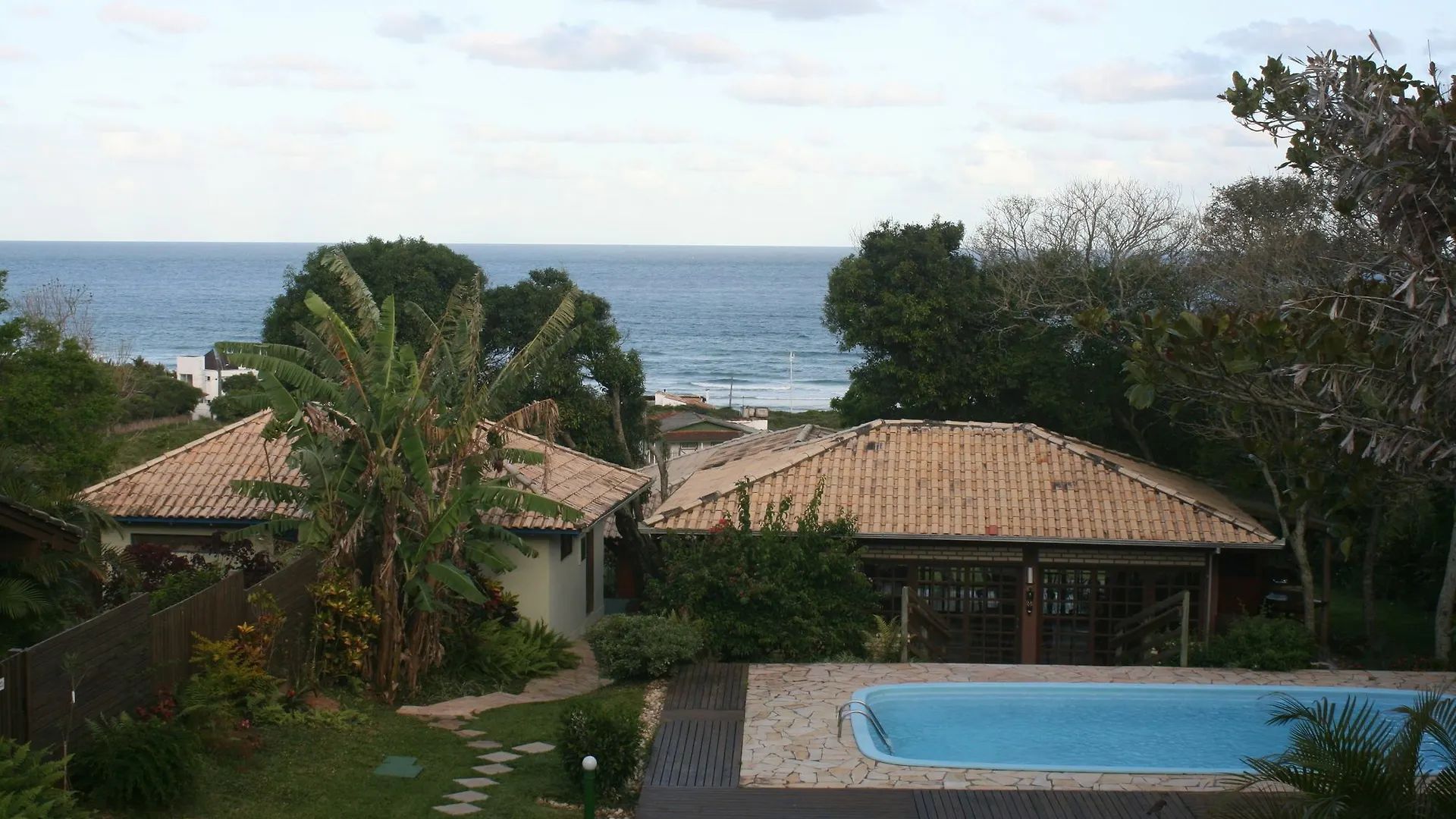 Casas com telhados de telhas de barro com vista para o mar e a piscina.
